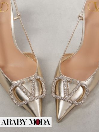 Gold Valentino heels with a front bearing a logo decorated with crystals